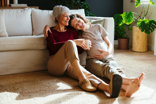 Mature woman spending time with her adult pregnant daughter at home