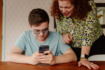 Woman smiling over boy's shoulder at phone