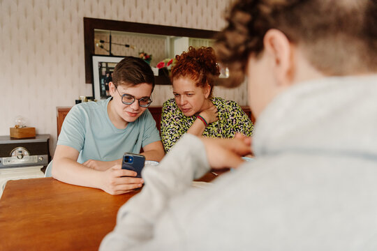 mother and teenager boy looking at screen of mobile phone