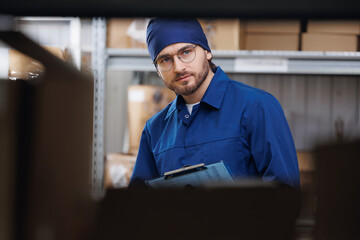 Worker in blue uniform use clipboard for control box in warehouse storage. Concept logistic center...