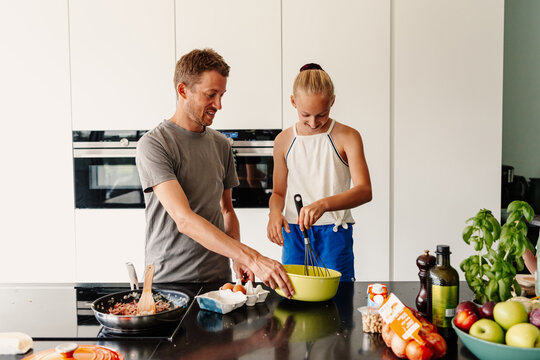Daughter and parent whisking eggs
