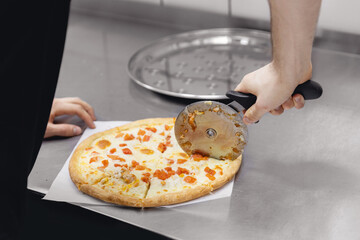 Pizzamaker worker cuts fresh pizza, business pizzeria concept