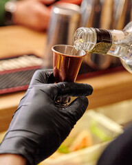 Bartender measuring spirits with jigger to balance taste of cocktail