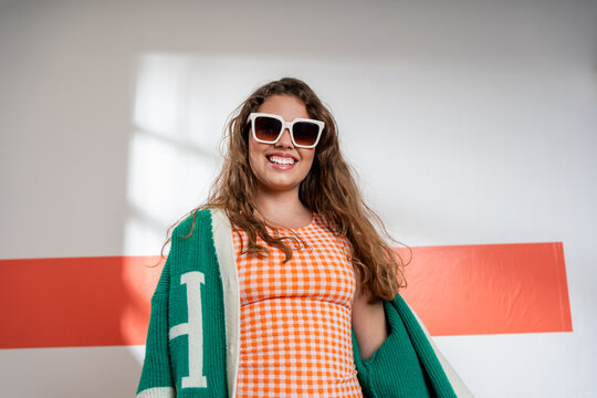 Smiling Young Woman in Sunglasses and varsity jacket 