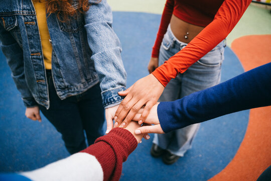Hands of different colors come together in a gesture of unity.