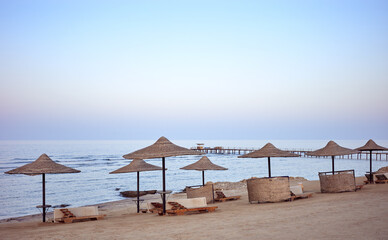 A tranquil beach with sun loungers and umbrellas at sunset, Marsa Alam region, Egypt.