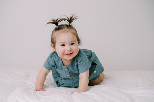 smiling one year old baby girl in blue dress