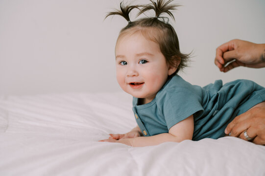 smiling one year old baby girl in blue dress