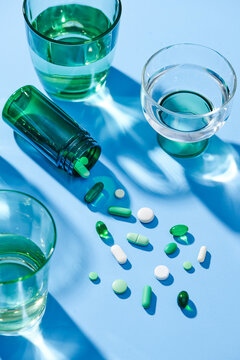 medicines with drinking water in glass over blue background