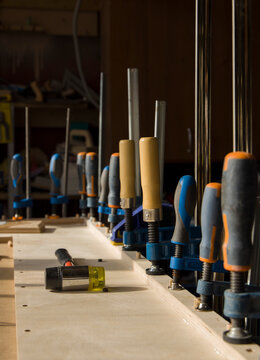 Row of Woodworking Clamps Securing a Workpiece on a Workbench 