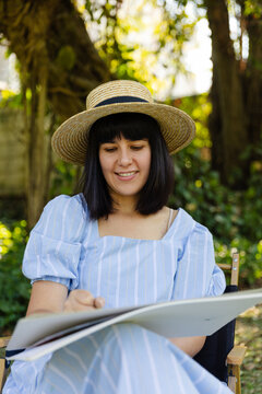 Happy woman sitting and drawing on sheet