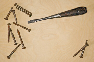 Screws and a screwdriver on a wooden board