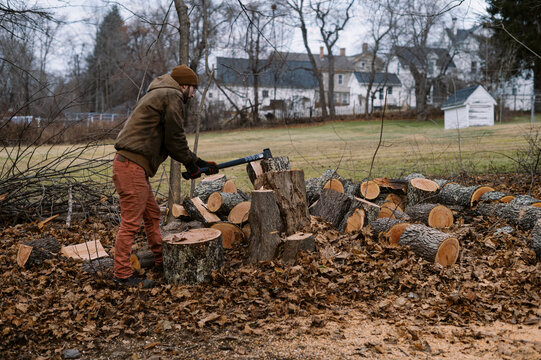 man splitting wood in his backyard with an axe