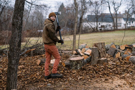 man splitting wood in his backyard with an axe