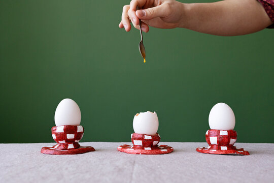 Three white eggs in red caged stands 
