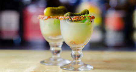 Shaken vodka and pickle juice with ice in a shot glass and garnished with small pickled cucumber and dill