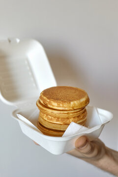 Anonymous hand holding styrofoam container with fresh pancakes 