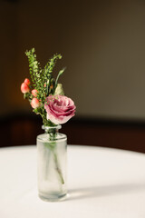 Glass jar with pink and green flowers on a table.