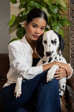 Indian Chinese woman at home with her Dalmatian dog. 
