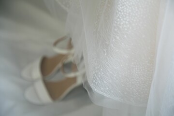 Closeup shot of the lace of a wedding dress and white heels