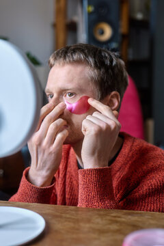 Man applying eye patches  in front of mirror