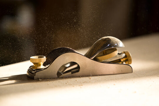 Wood shavings fly from a plane tool during woodworking 