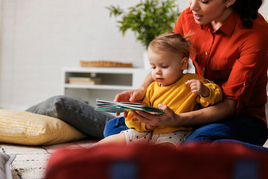 woman with daughter reading picture book at home - Powered by Adobe