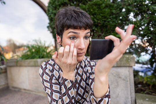 Woman applying concealer on dark circles.