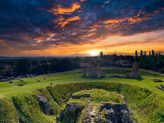 Sun setting over ancient castle ruins with cloudy sky in twilight