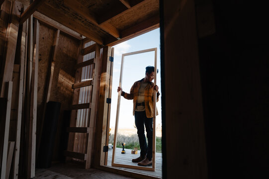 man framed in door while holding a door he just built