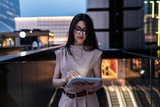 Woman freelancer browsing digital tablet under city lights