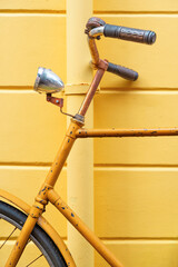 Closeup of a yellow bicycle against a yellow wall.