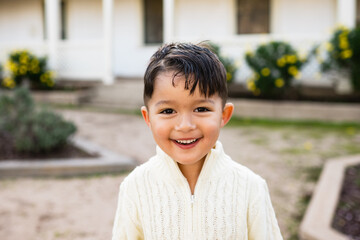 Portrait of smiling dark haired two year old boy outside 