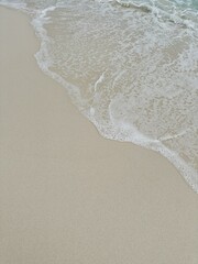 Ocean wave over white sand beach close up