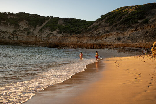 Kids running on an empty beach at golden time in Australia