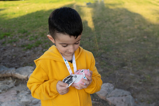 Boy Smiling At Instant Camera In Park.