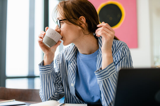 A woman drinks coffee working at home