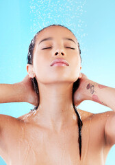 Naklejka premium Woman, washing hair or showering in blue studio background for cosmetics, hygiene and wellness. Female person, eyes closed and water cleaning head for grooming, skincare and treatment or bath