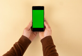 Person holding a smartphone with green screen