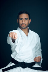 Karate, master and portrait of man in martial arts on studio, black background or practice exercise. Serious, fight and person with self defence skill, technique or fighter gesture action with hands