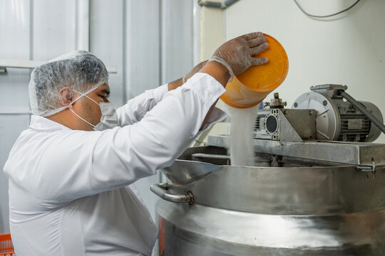 Worker adding sugar into an industrial kitchen pot