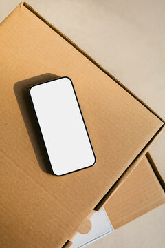 Mockup Smartphone with white screen on Cardboard parcel