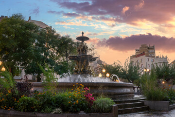 Spectacular fountain of the Muses in the town of Huesca decorated with plants and flowers at sunset