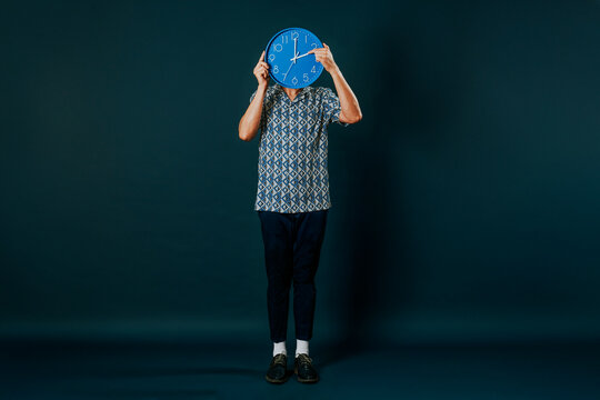 man reseting a clock standing on a blue background