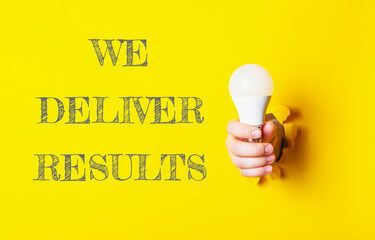 A person holding a light bulb with the words We Deliver Results written below