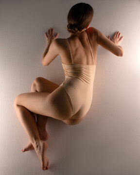 The girl in beige bodysuit performing on the ground in studio.