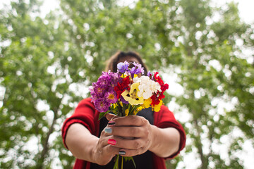 a woman in a red dress is holding colorful flowers in her hands