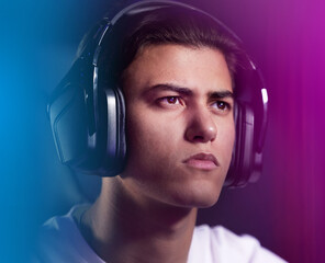 Neon, face and man as pro gamer with playing on computer for online video games and serious. Headphones, esports and hobby at home with intense contest or challenge and competition with confidence © peopleimages.com