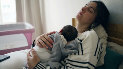 Peaceful mother and newborn baby asleep together during initial week of life, mom trying to rest...
