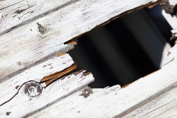 Close-up of Weathered Wooden Surface with Large Hole, Exposing Decayed and Peeling Paint, Depicting...